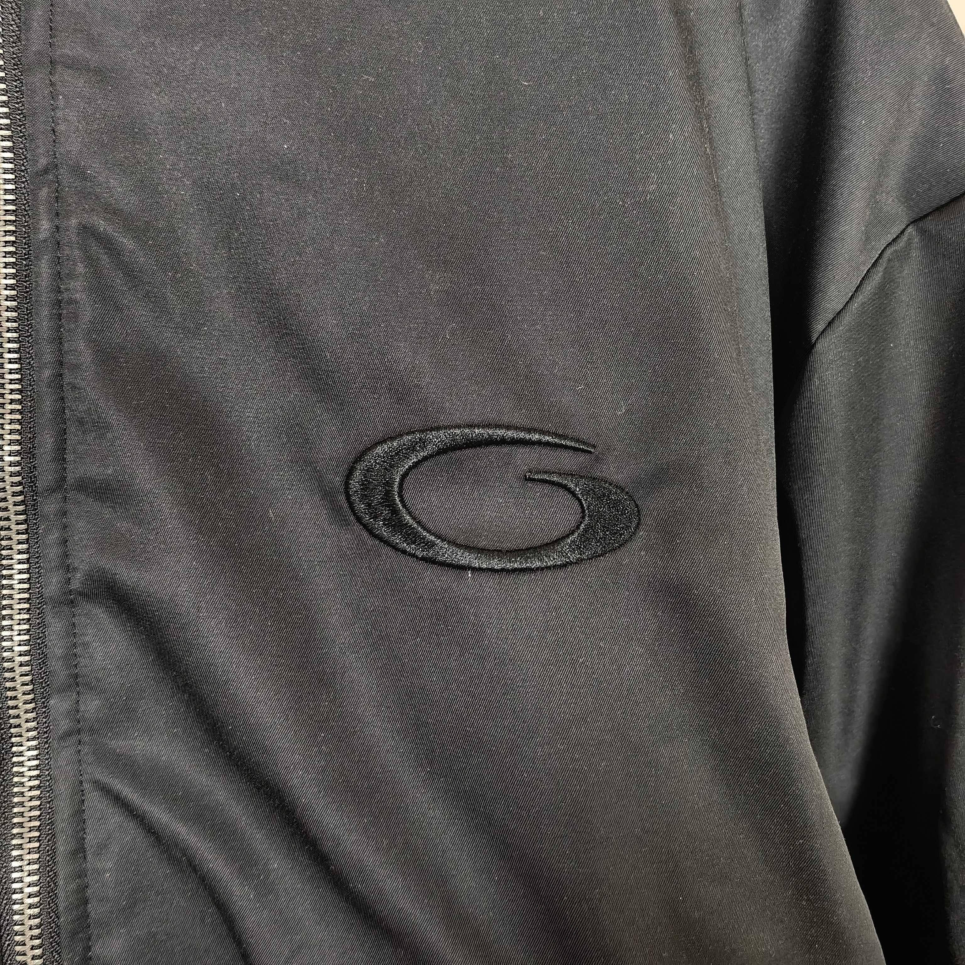 Oval embroidered logo patch on dark bomber jacket sleeve