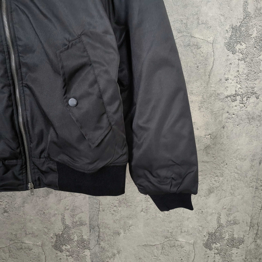 Dark bomber jacket with front zipper, snap pocket, and ribbed cuffs