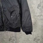 Dark bomber jacket with front zipper, snap pocket, and ribbed cuffs
