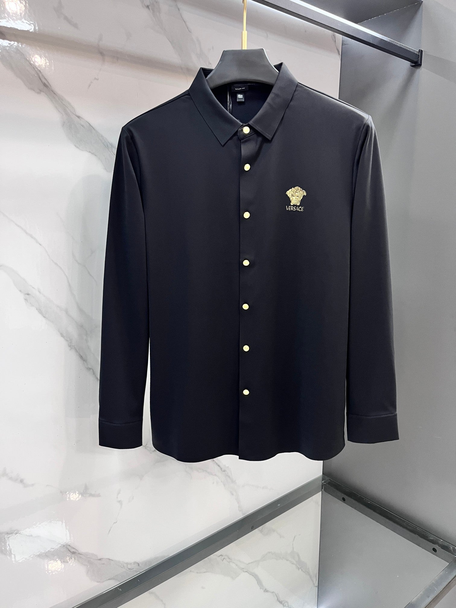 Navy long-sleeve button-up shirt with gold buttons and small chest logo crest