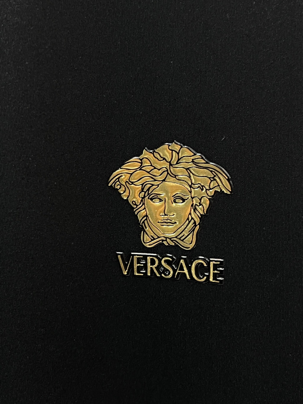Gold Medusa logo with VERSACE text on black fabric