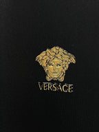 Gold Medusa logo with VERSACE text on black fabric
