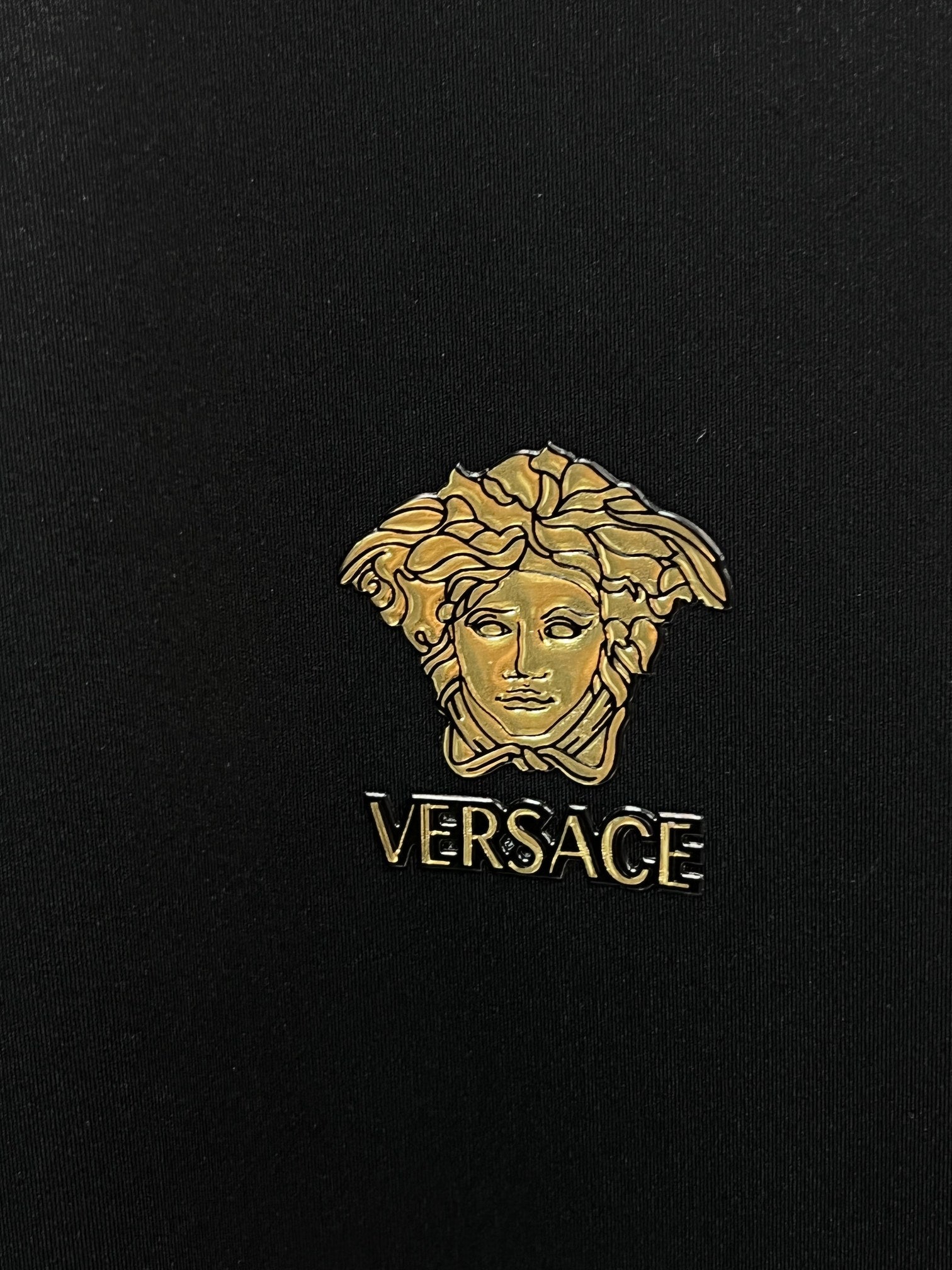 Gold Medusa logo with VERSACE text on black fabric