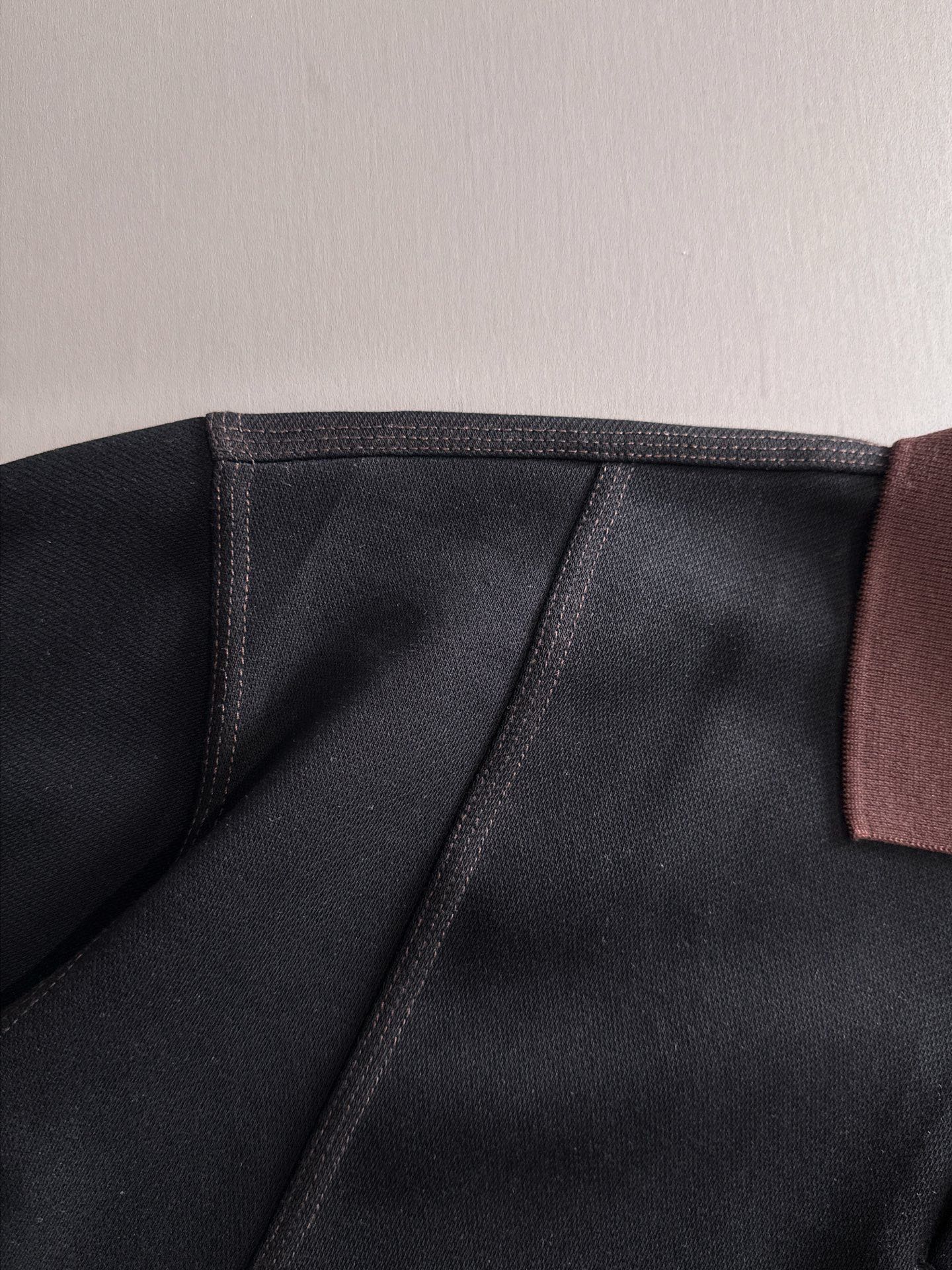 Black sweatshirt collar seam with burgundy trim panel