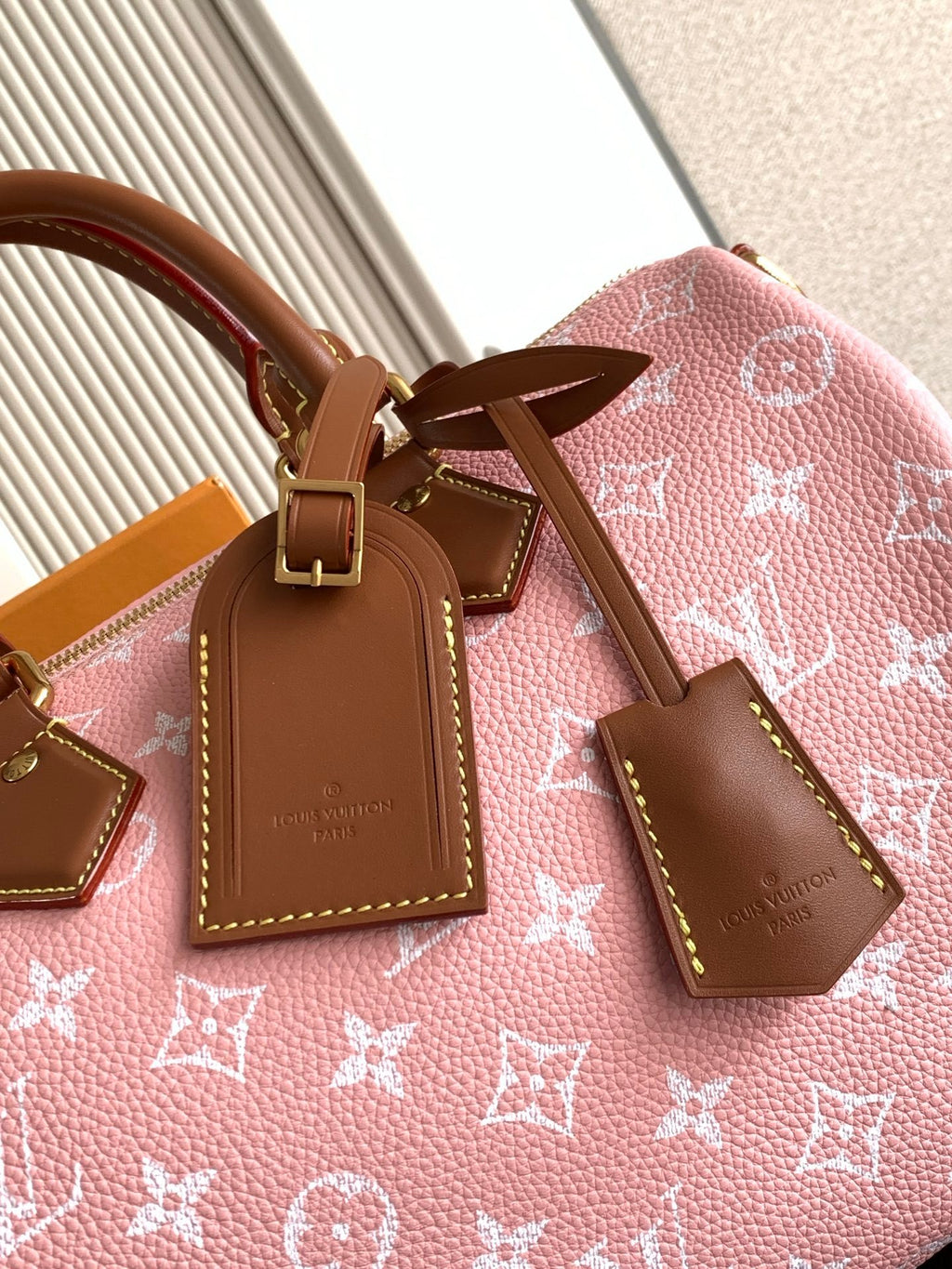 Louis Vuitton handbag top close-up with pink monogram canvas, tan leather tags and bow detail