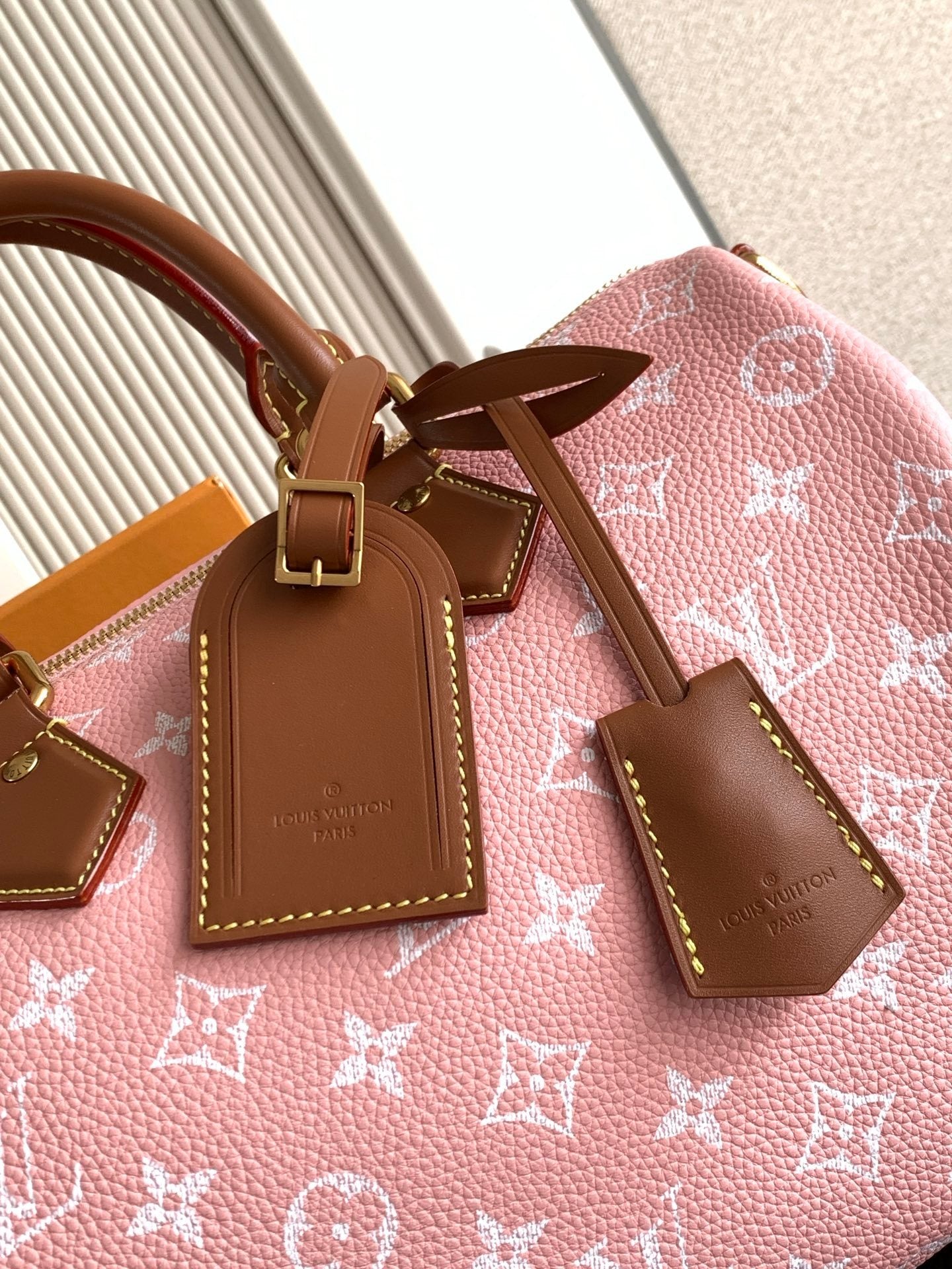 Louis Vuitton handbag top close-up with pink monogram canvas, tan leather tags and bow detail