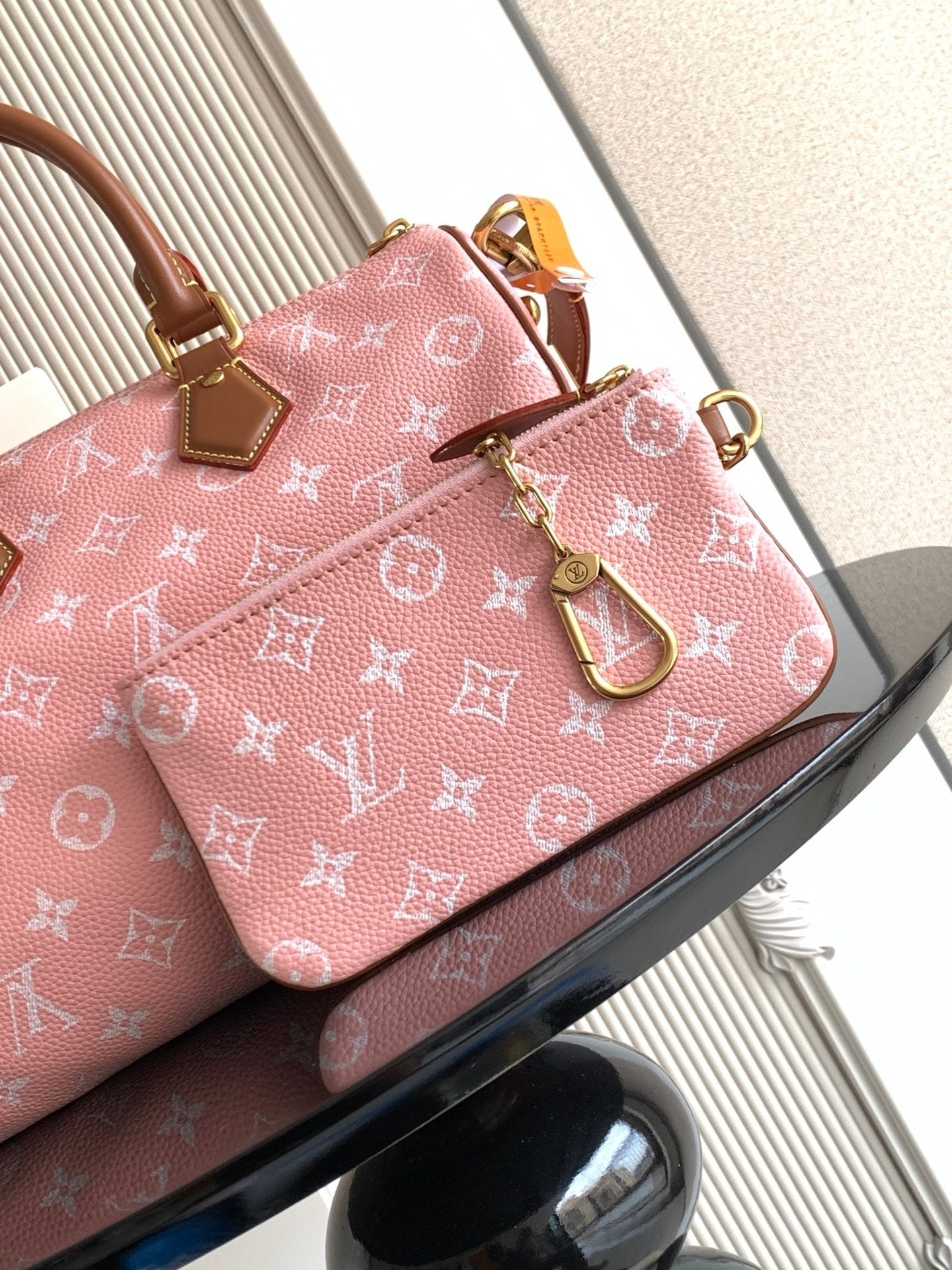 Louis Vuitton pink monogram handbag front view with tan leather handles and strap