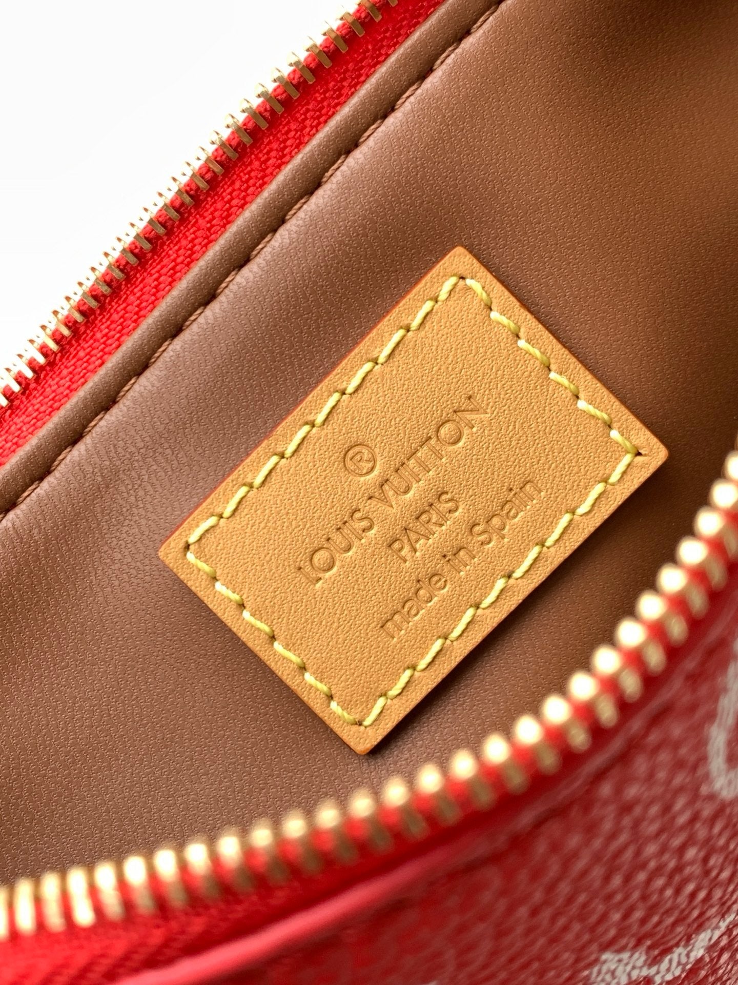 Louis Vuitton handbag leather interior patch with stitched logo and red zip edge