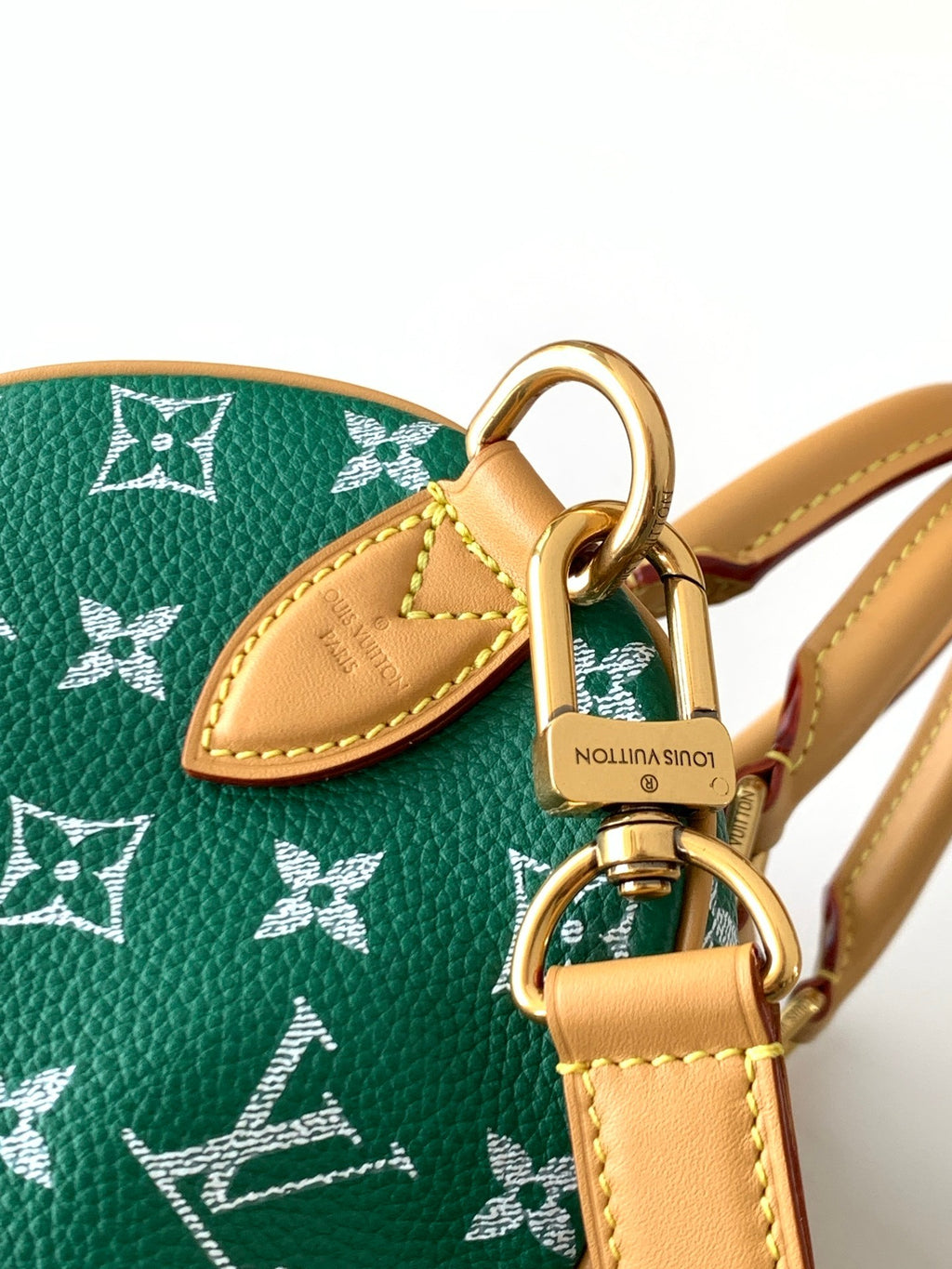 Louis Vuitton green monogram bag closeup with tan leather tag and metal rings