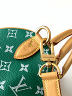 Louis Vuitton green monogram bag closeup with tan leather tag and metal rings
