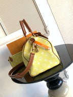 Louis Vuitton bag with yellow monogram, brown crossbody strap, and front zipper pocket