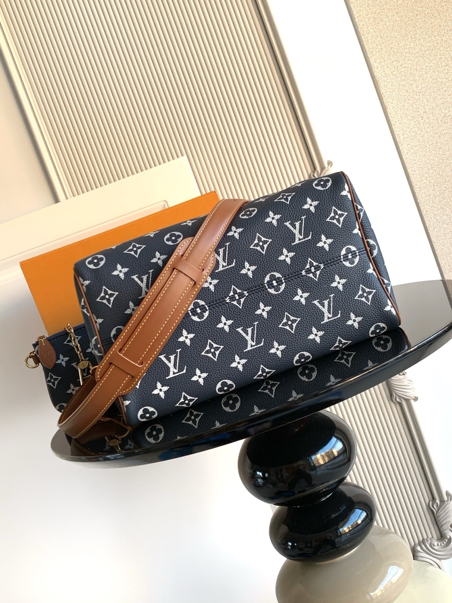 Designer handbag in navy monogram canvas with tan crossbody strap and gold-tone hardware