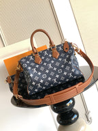 Designer handbag in navy monogram canvas with tan strap, top handles, and gold hardware