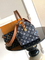 Designer handbag with navy monogram canvas, tan shoulder straps, and gold-tone hardware