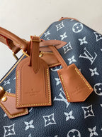 Designer handbag charm tags on navy monogram canvas with tan leather and gold accents
