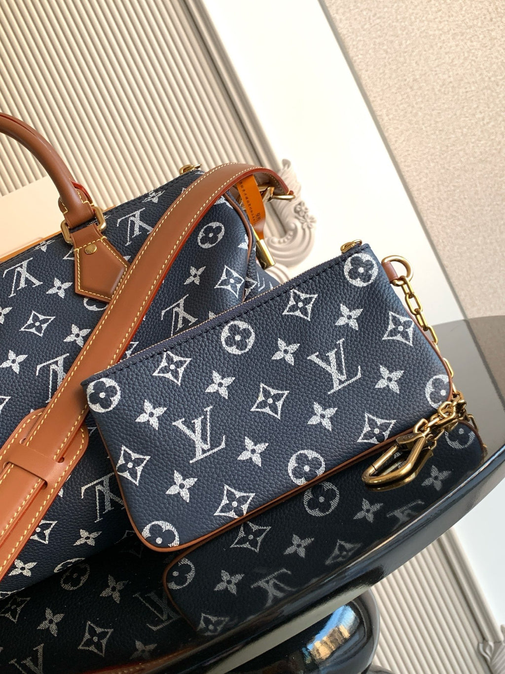 Designer handbag in navy monogram canvas with tan strap and gold-tone hardware on sides