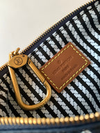 Designer handbag interior close-up with gold zipper pull and tan leather brand patch