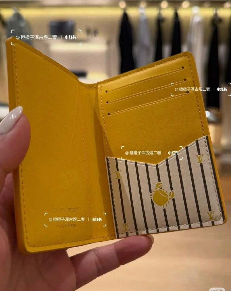 Small Louis Vuitton card holder, yellow, open with striped center panel and fruit emblem