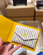 Small Louis Vuitton card holder close-up, yellow with striped panel and fruit emblem
