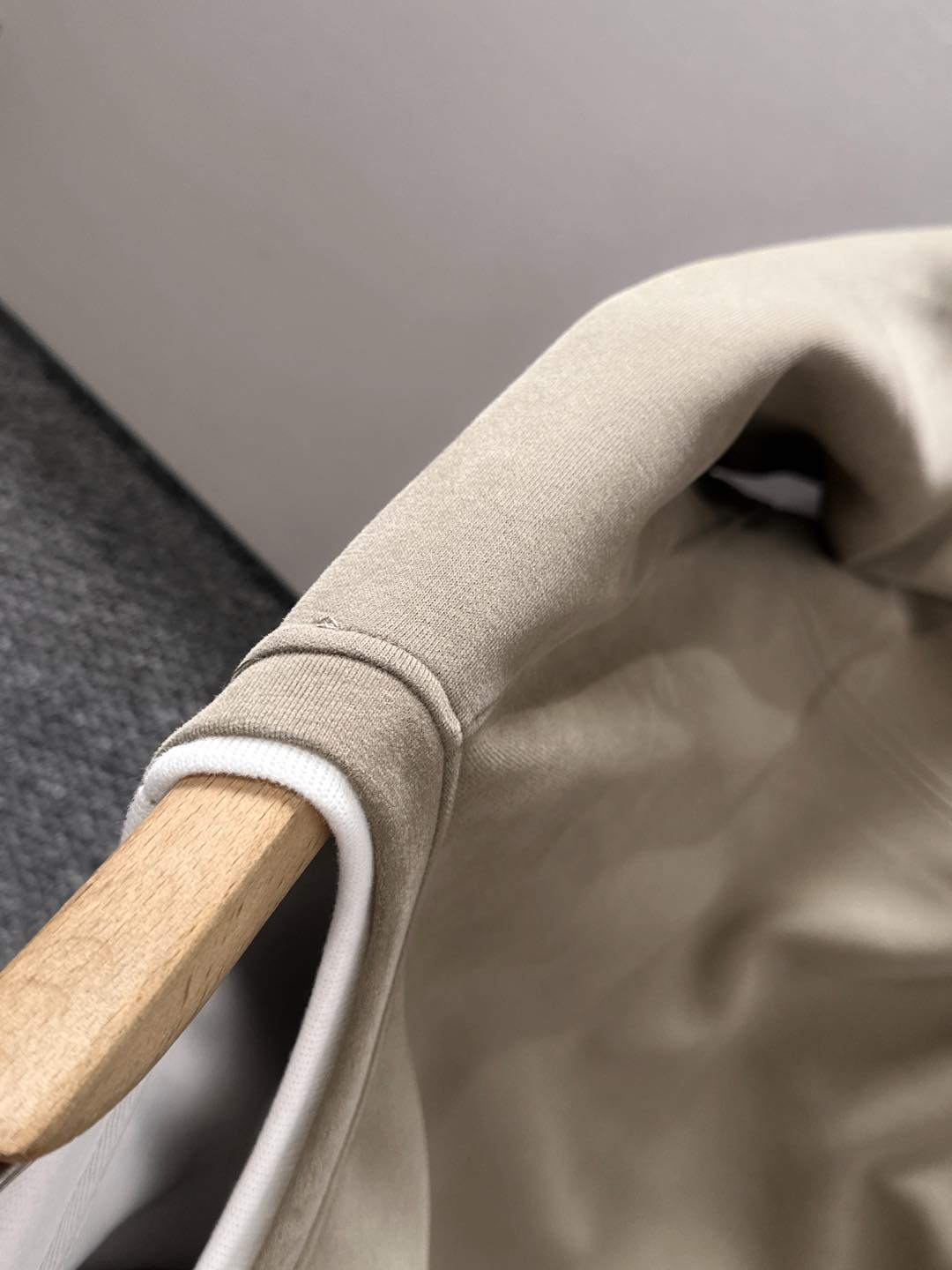 Beige sweatshirt shoulder and crewneck collar close-up on hanger