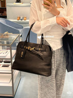 MiuMiu leather tote bag in dark brown with gold hardware and front logo tag, handheld