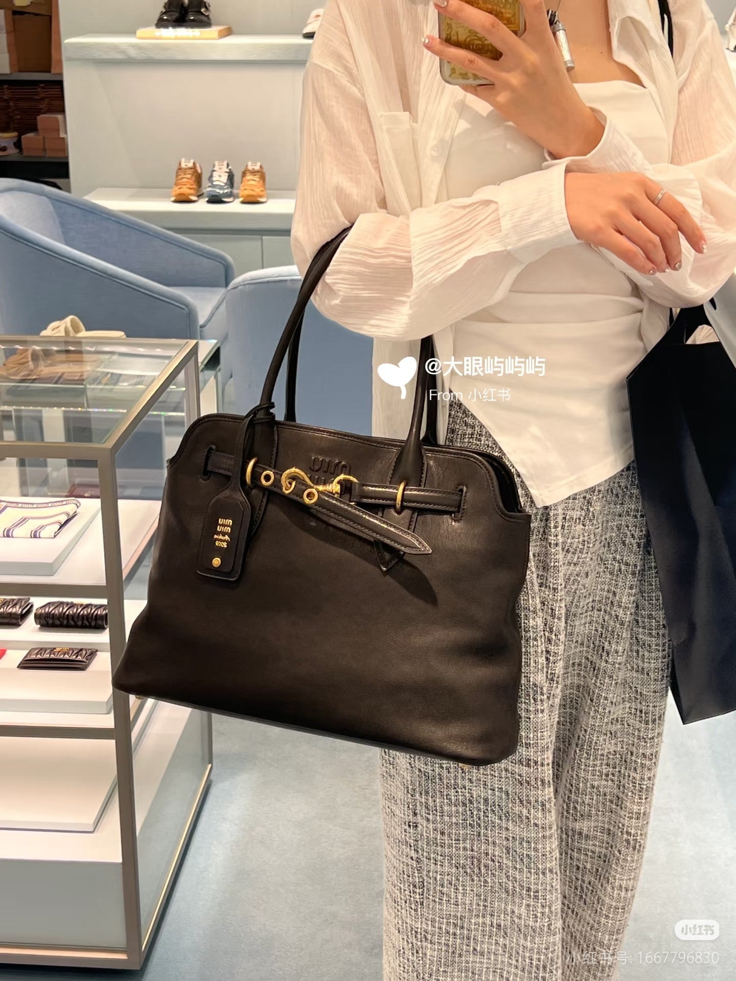 MiuMiu leather tote bag in dark brown with gold hardware and front logo tag, handheld