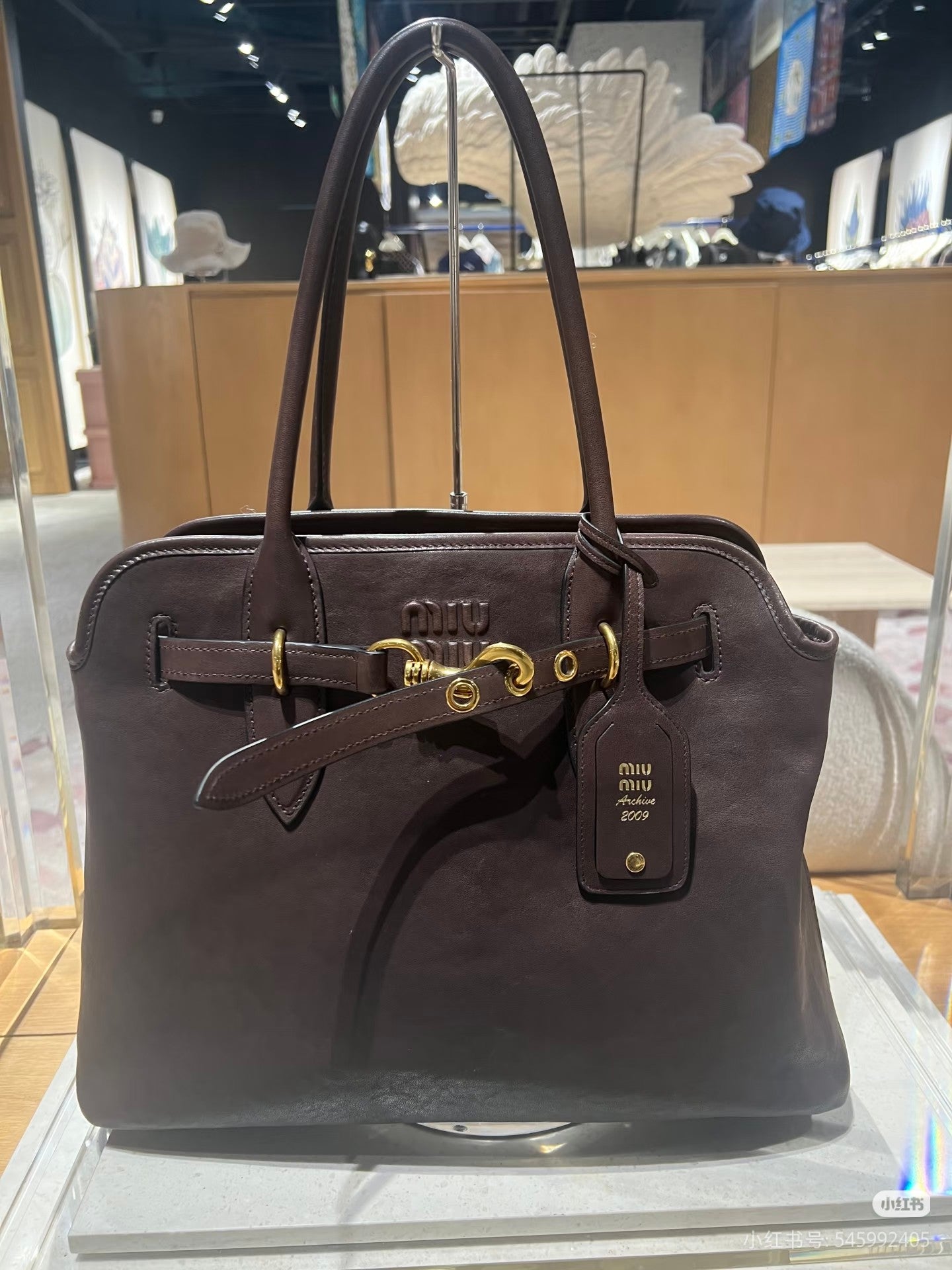 MiuMiu leather tote bag in dark brown with gold buckle detail and front logo tag