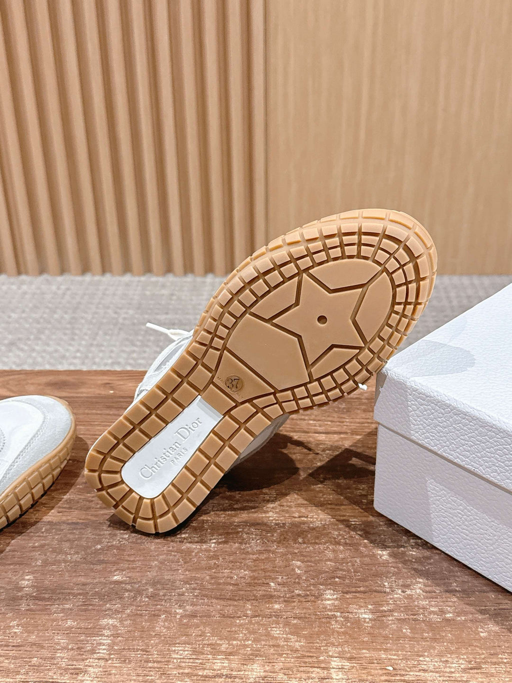 Sneaker outsole view with tread and “Dior” logo on rubber base