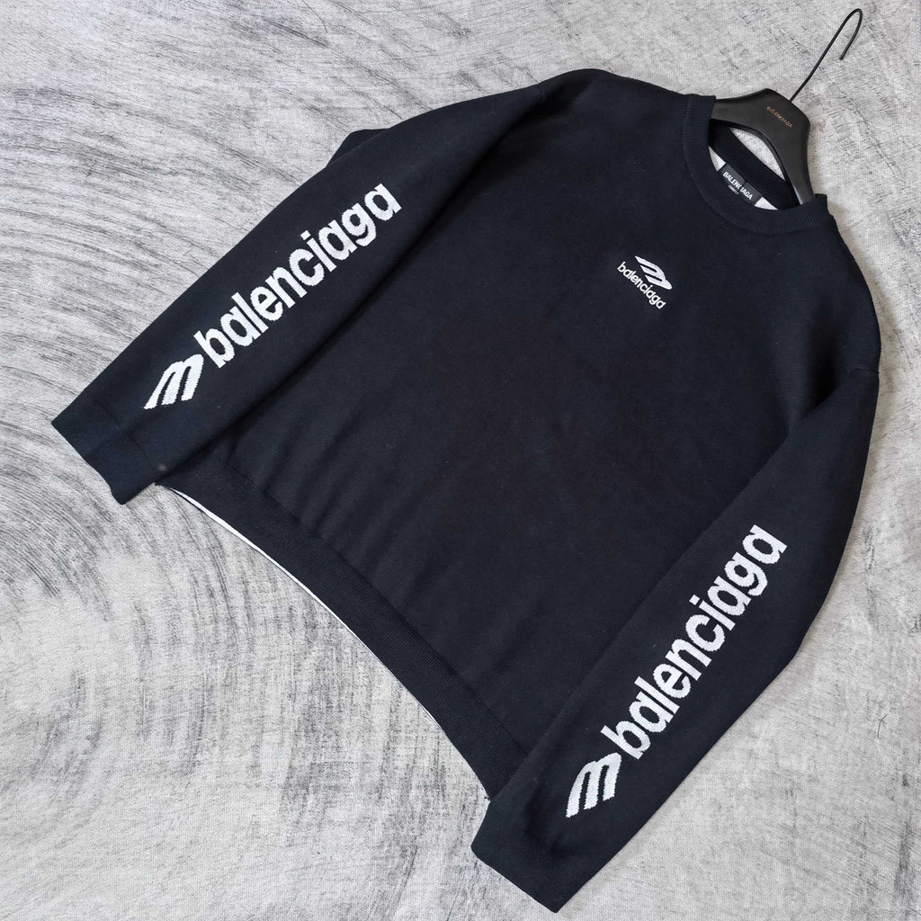 Balenciaga dark sweater laid flat, long sleeves with repeating sleeve logo text