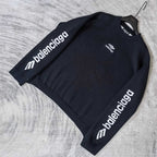 Balenciaga dark sweater laid flat, long sleeves with repeating sleeve logo text