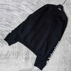 Balenciaga dark crewneck sweater laid flat, side view with sleeve logo stripe