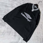 Black long-sleeve V-neck shirt laid flat with Balenciaga chest logo and striped collar.