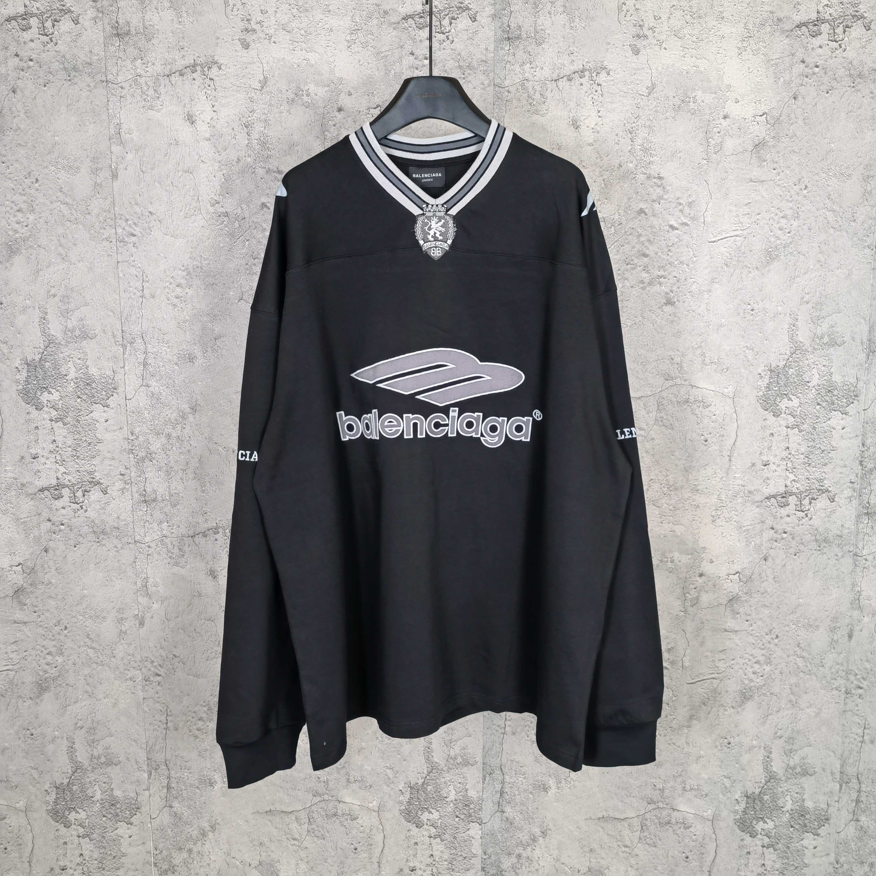 Black long-sleeve V-neck shirt with striped collar and Balenciaga front logo print.