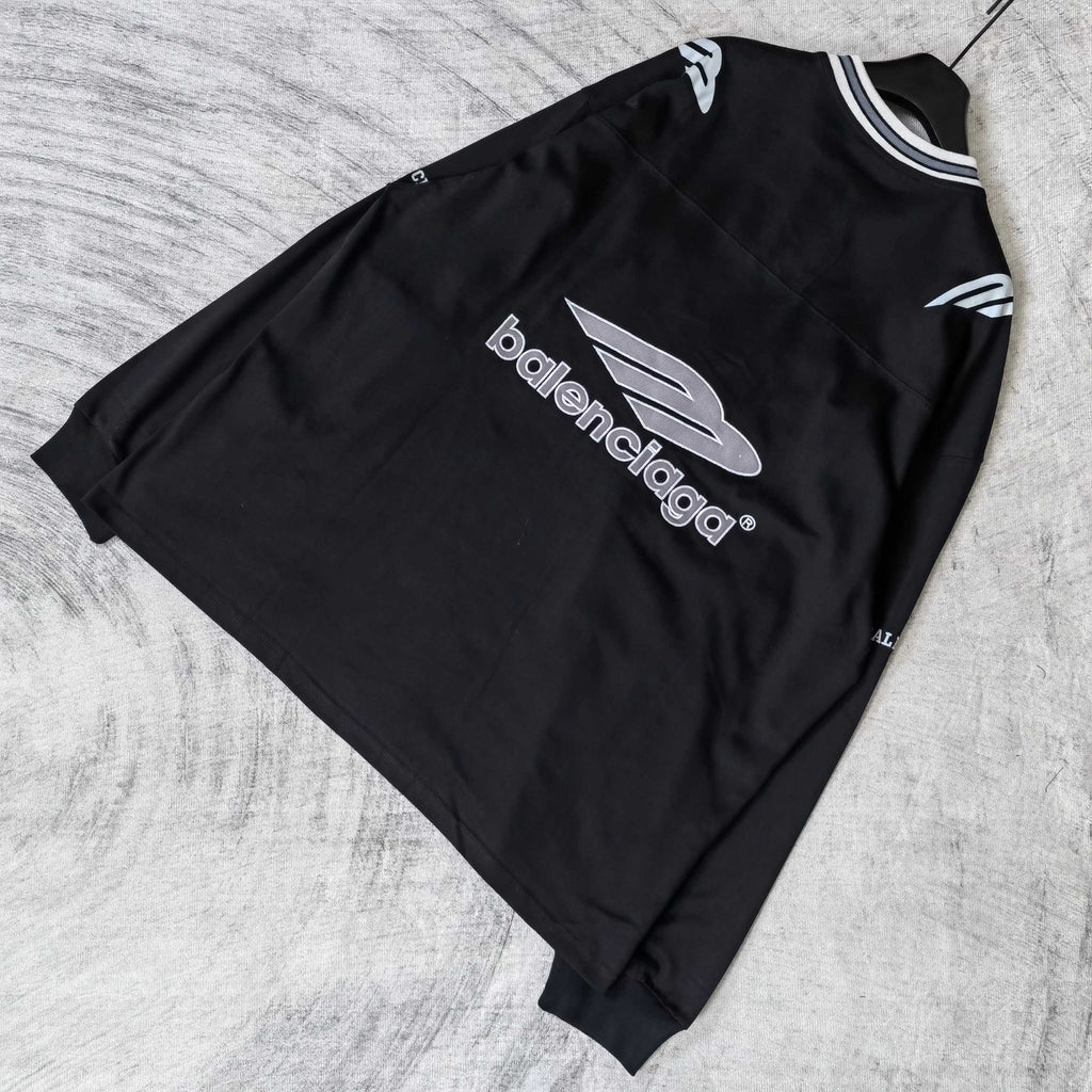 Black long-sleeve V-neck shirt laid flat with centered Balenciaga logo and sleeve graphics.