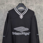 Black long-sleeve V-neck shirt with striped rib collar and crest pendant logo at chest.