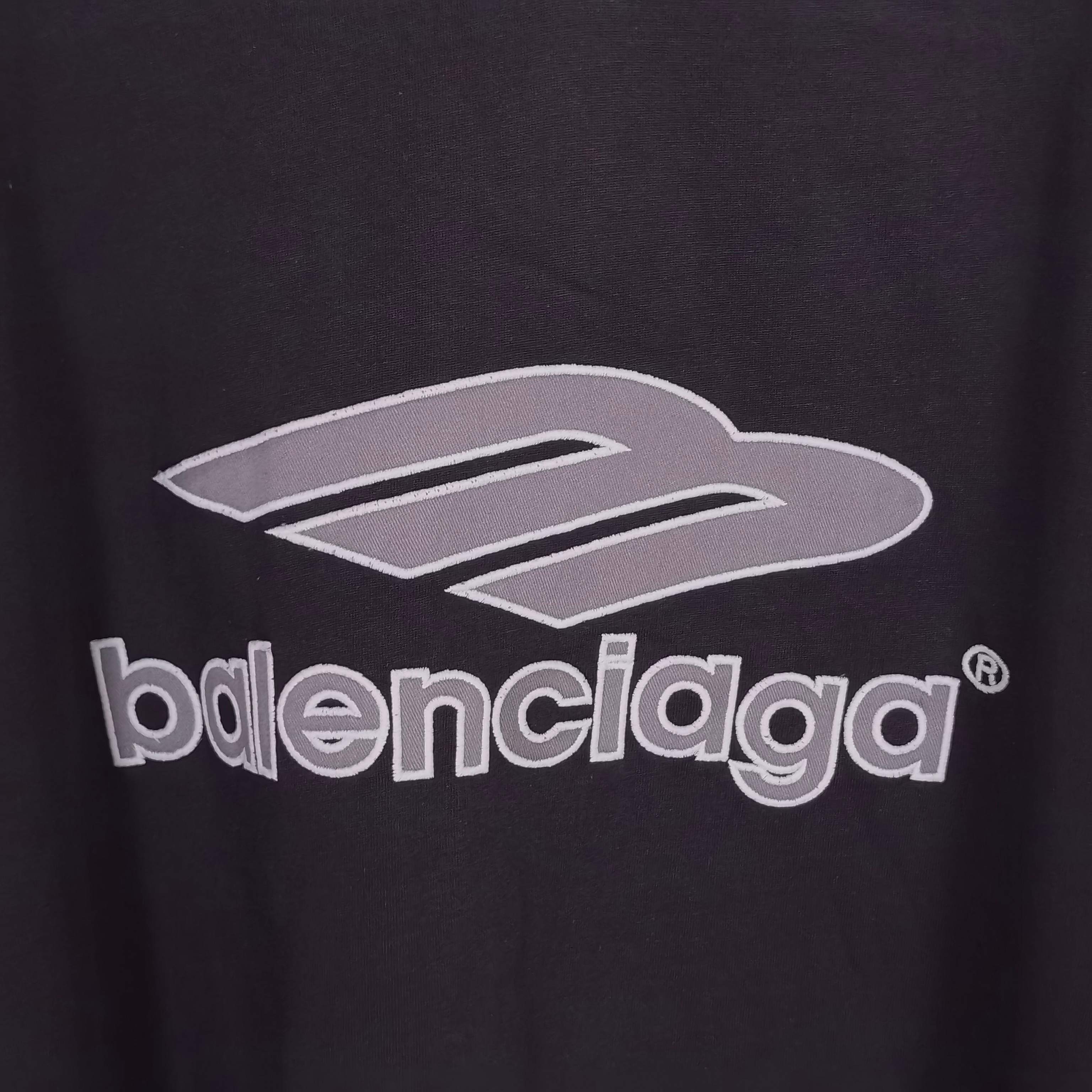 Balenciaga logo graphic close-up on black long-sleeve V-neck shirt fabric.