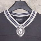 Black long-sleeve V-neck shirt close-up of striped collar and crest pendant logo.