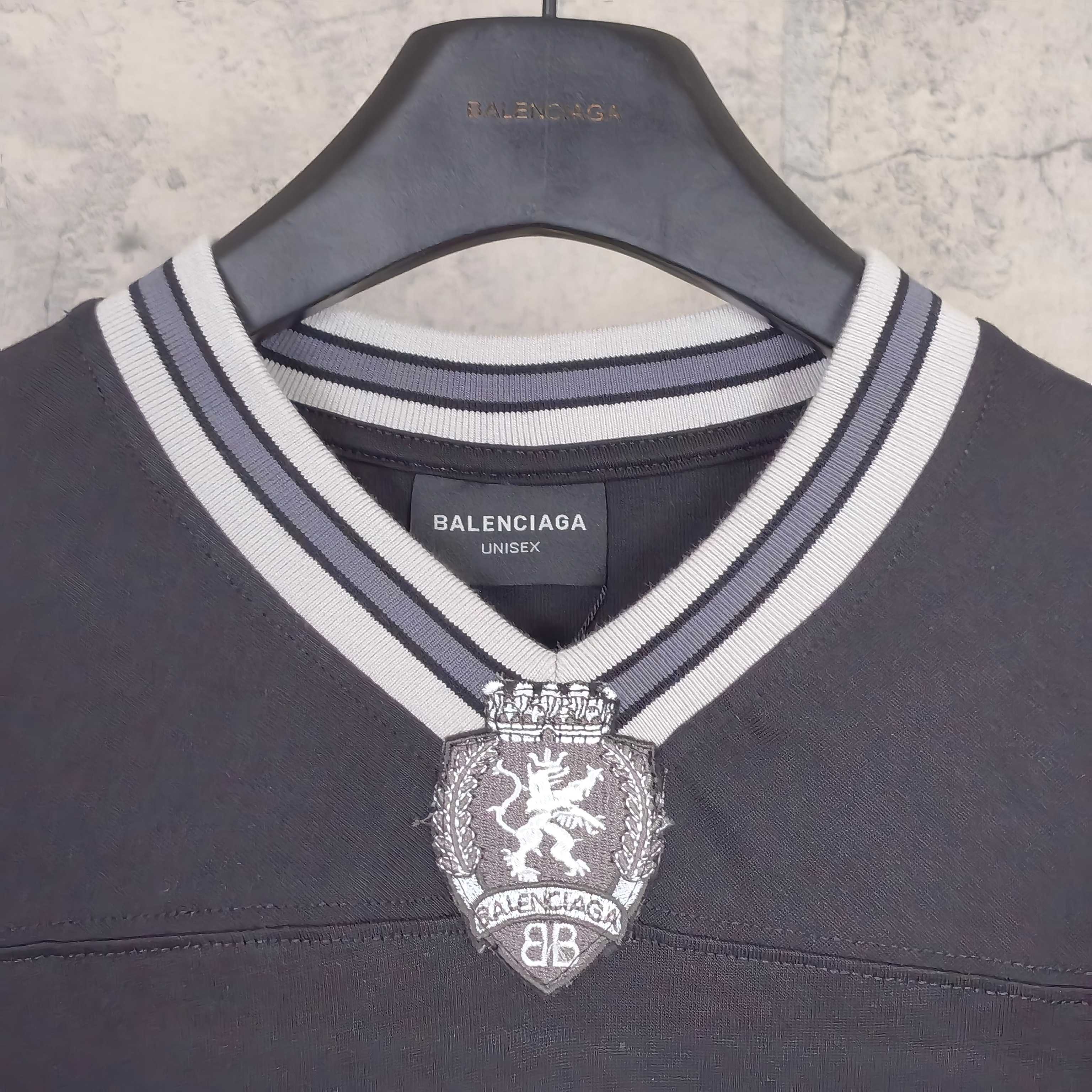Black long-sleeve V-neck shirt close-up of striped collar and crest pendant logo.