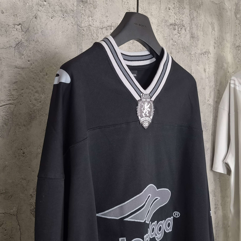 Black long-sleeve V-neck shirt front view with striped rib collar and crest pendant logo.