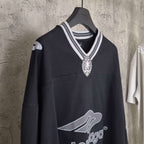 Black long-sleeve V-neck shirt front view with striped rib collar and crest pendant logo.