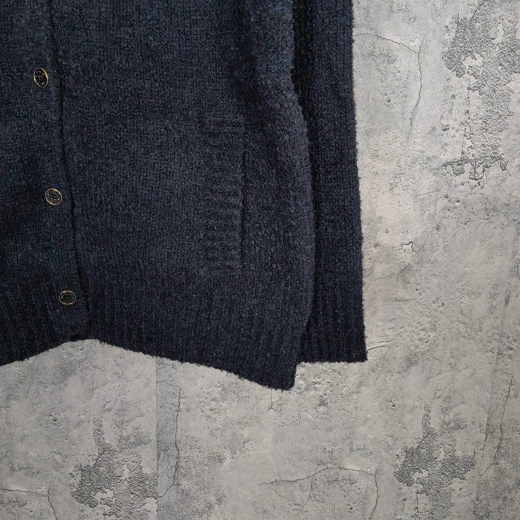 Dark long-sleeve jacket front with metal buttons and curved hem