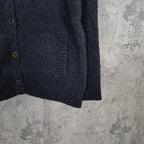 Dark long-sleeve jacket front with metal buttons and curved hem