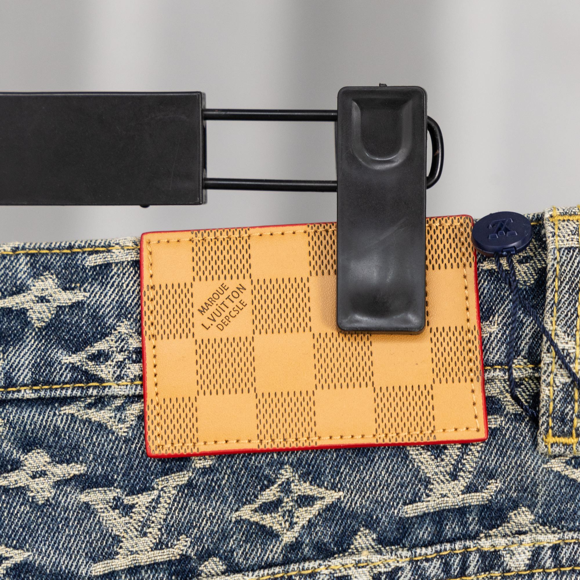 Louis Vuitton monogram denim pants with matching orange fabric tag and belt loops