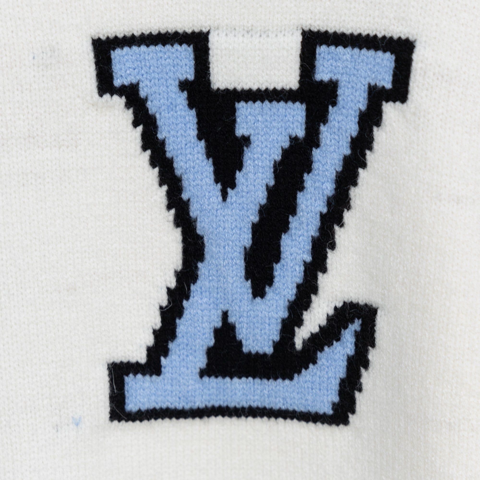 White knit sweater with oversized blue and black LV-style monogram on chest