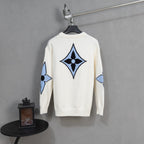 White knit sweater with large blue and black diamond logo emblem on back