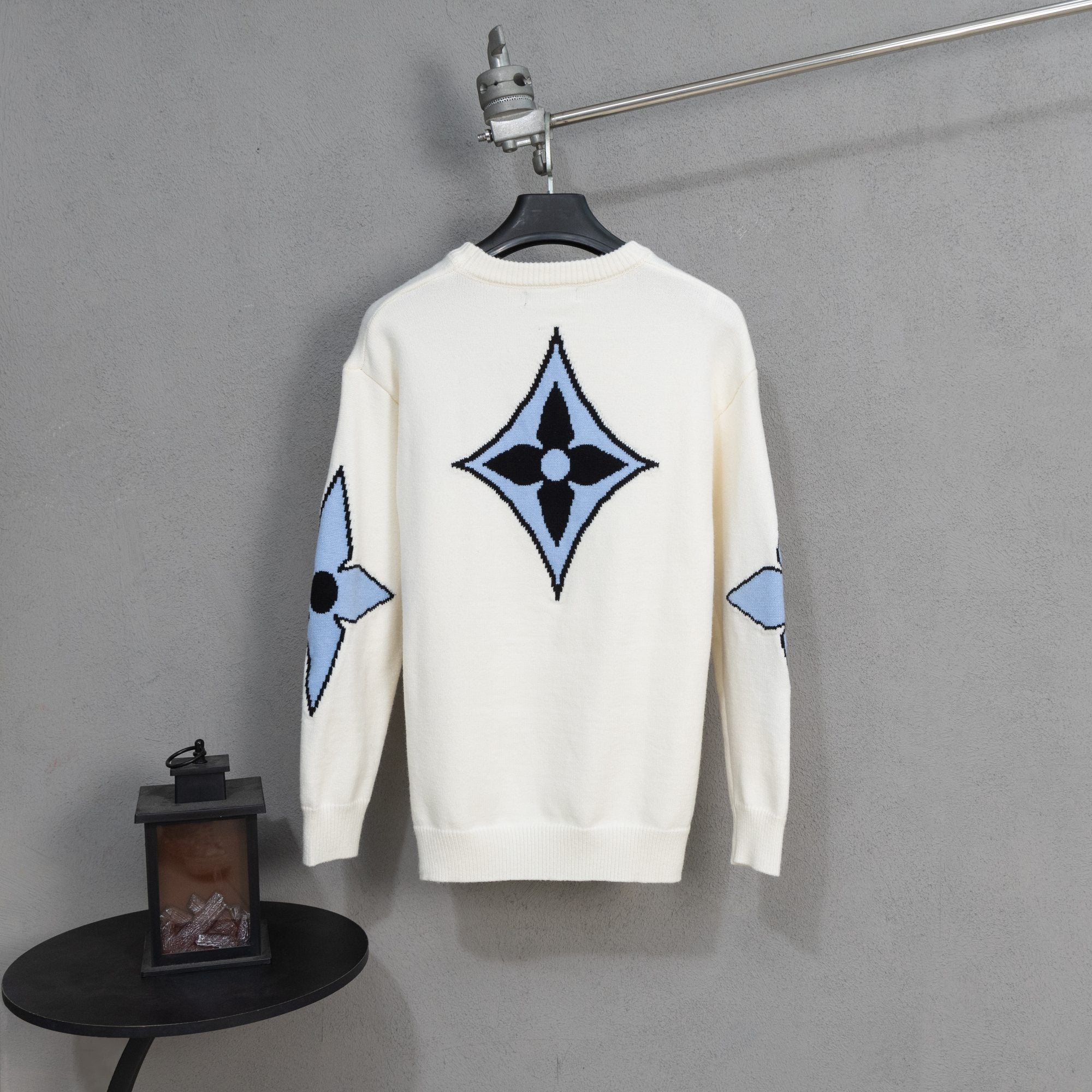 White knit sweater with large blue and black diamond logo emblem on back