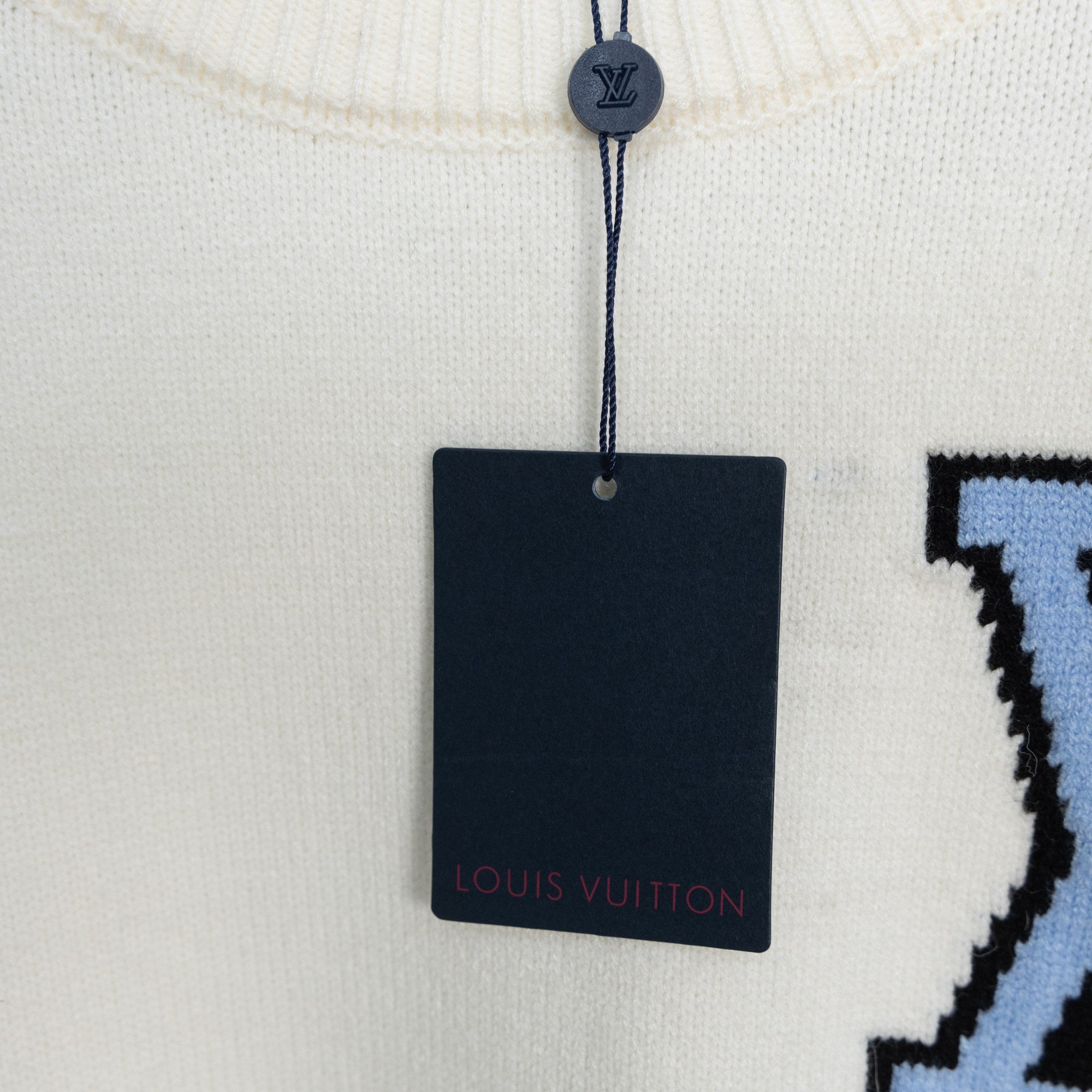 White sweater neckline with hanging Louis Vuitton tag and knit texture detail