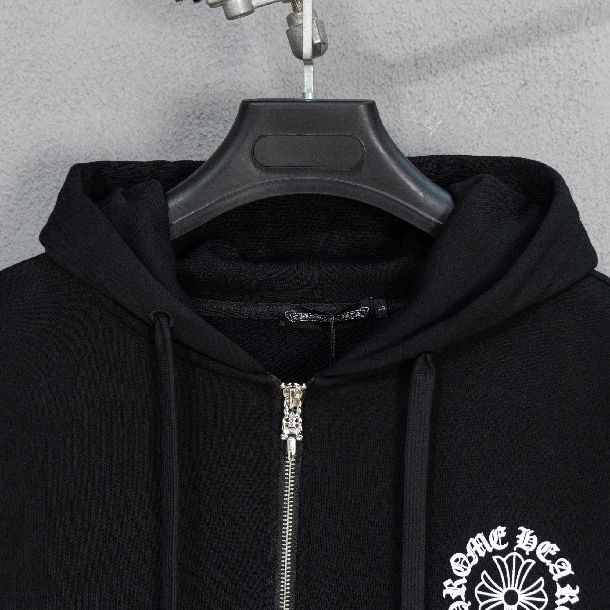 Black zip hoodie close-up with silver zipper and drawstring hood