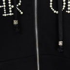 Black hoodie close-up of silver zipper and pearl beaded pocket detailing
