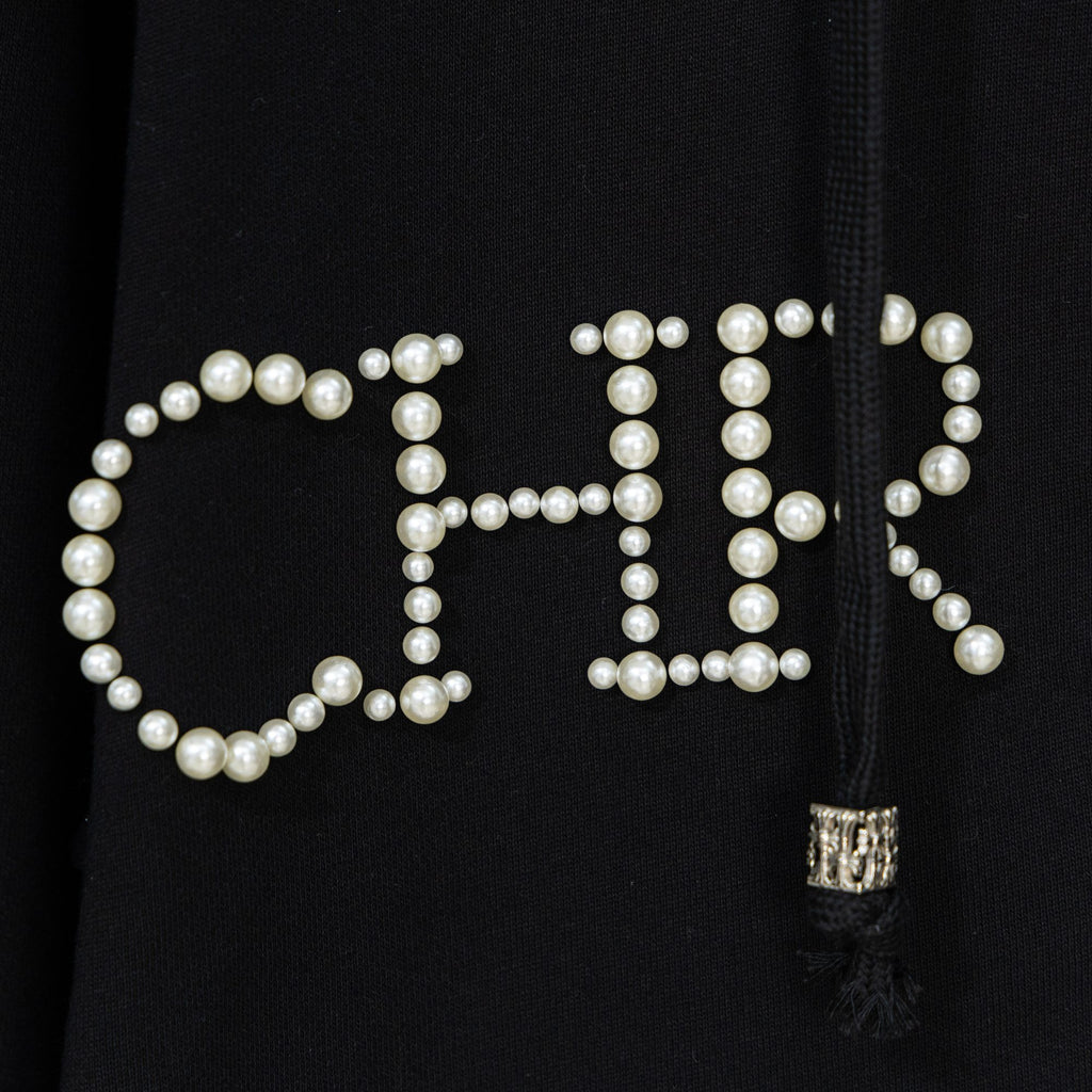 Black hoodie close-up of pearl beaded lettering with small zipper pull tassel